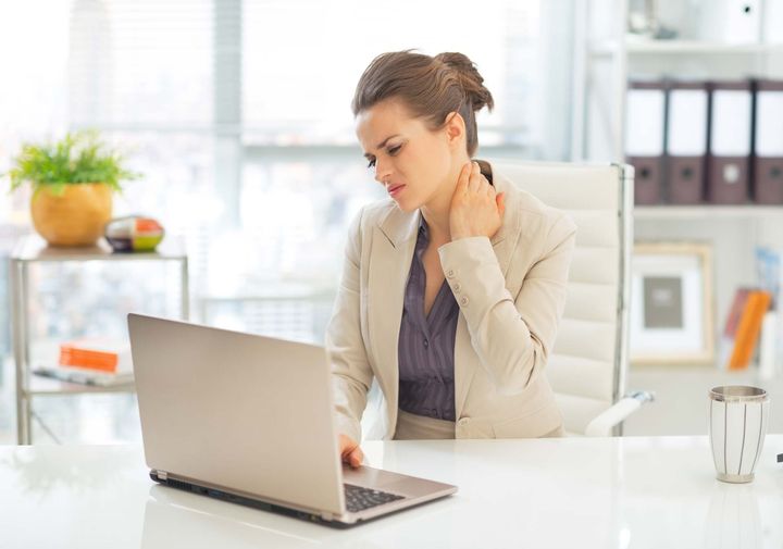 Woman massaging neck at computer working